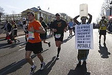 Une Gambienne prend le départ du marathon de Paris en marchant, un bidon d'eau sur la tête
